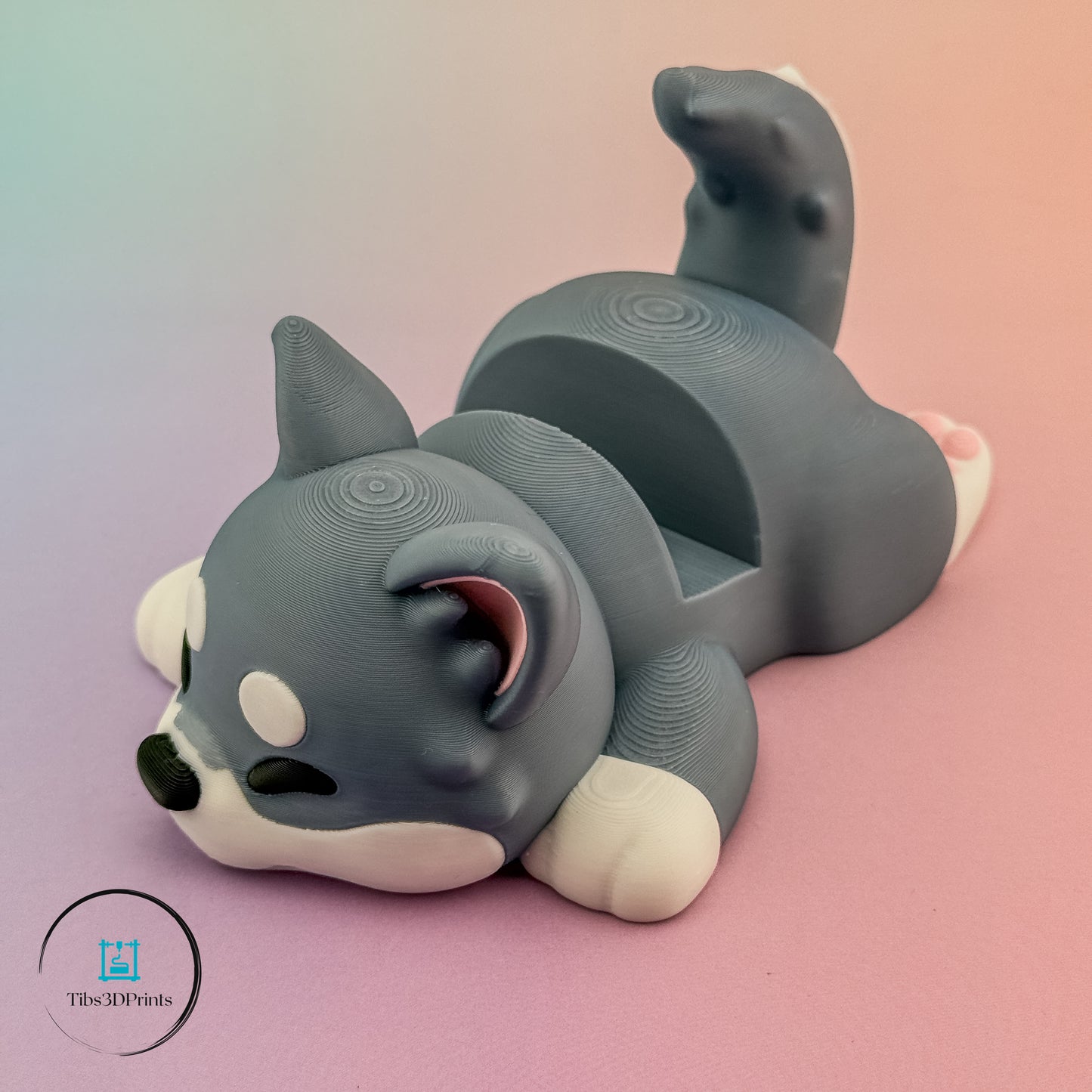 Sleepy Pup phone stand holding phone on desk, 3D printed by Tibs3DPrints